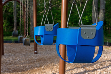 Empty playground with swings and baby seats in the early morning light.の写真素材