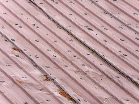 Old red metal roofing with damage from age.の写真素材