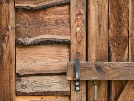 Close view of the door latch of a rustic door and siding on a cabin.