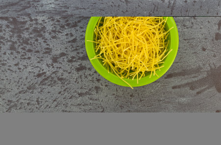 Top view of a small bowl filled with thin soup noodles atop a gray countertop.の写真素材