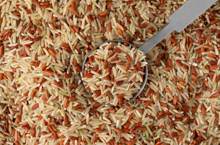 Overhead view of using a tablespoon to take a portion of long grain brown rice and red rice.の写真素材