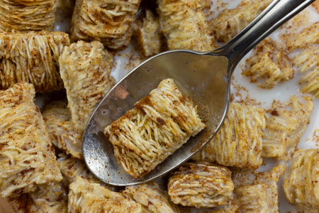 Very view of taking a spoonful of wheat cereal with milk and cinnamon.
