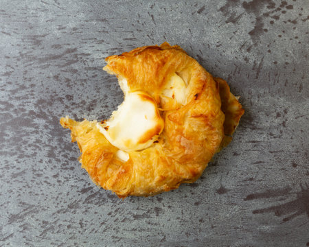 Overhead view of a delicious cream cheese danish missing a bite on a gray mottled tabletop illuminated with natural light.の写真素材
