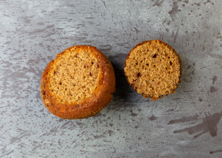 Overhead view of a freshly baked cinnamon muffin cut in half on a gray mottled background...
