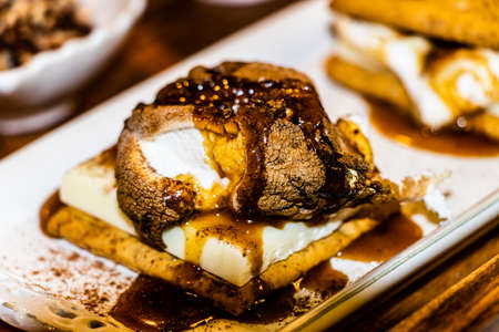 White chocolate and melted marshmallow graham cracker smore covered in birch whiskey toffee sauce and cinnamon, a sweet and tasty dessert while entertaining friends and familyの写真素材