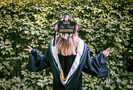 A humorous image of a woman in a convocation cap and gown in front of a green leaf hedge with her...