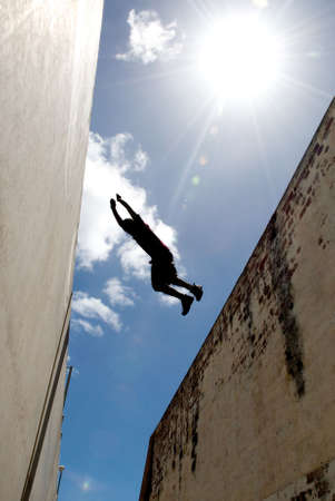 Person jumping over gap between buildingsの写真素材