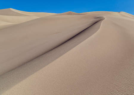Magestic sand dune rises towards a clear blue skyの写真素材