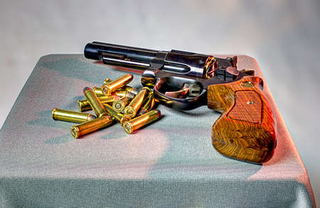 Bullets ready to use beside a revolver on a table.の写真素材