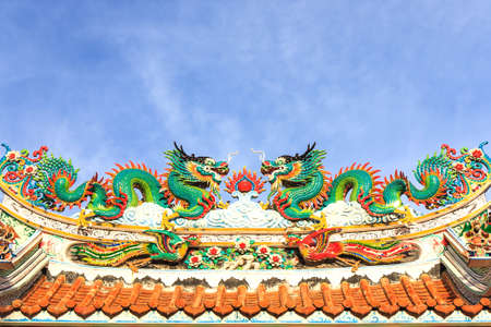 Twin dragons statue on the roof of Chinese temple with blue skyの写真素材