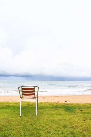 Empty chairs on green grasses near  beach in the morningの写真素材