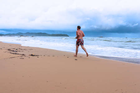 Senior man jogging on beach in the morningの写真素材