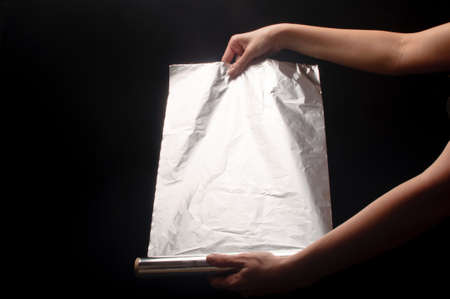 woman holding an aluminum foil on a black backgroundの写真素材