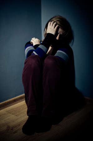 sad woman sitting alone in a empty roomの写真素材
