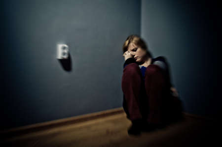 sad woman sitting alone in a empty roomの写真素材