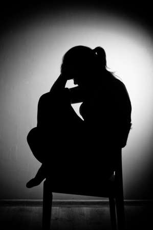 sad woman sitting alone in a empty room - black and whiteの写真素材