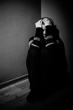 sad woman sitting alone in a empty room - black and whiteの写真素材