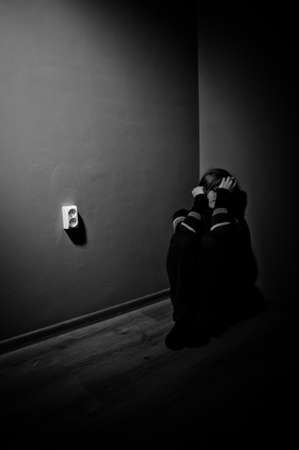 sad woman sitting alone in a empty room - black and whiteの写真素材