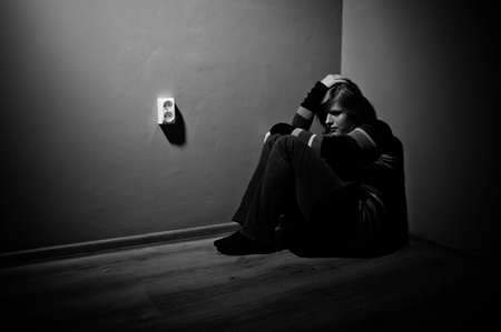 sad woman sitting alone in a empty room - black and white