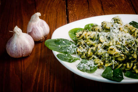 pasta with spinach on a wooden table - decorated with garlicの写真素材