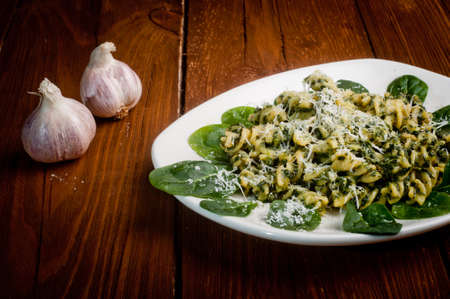 pasta with spinach on a wooden table - decorated with garlicの写真素材