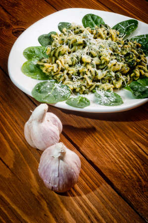 pasta with spinach on a wooden table - decorated with garlicの写真素材