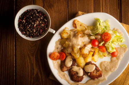 beef in pepper sauce with baked potatoes and salad  On a wooden backgroundの写真素材