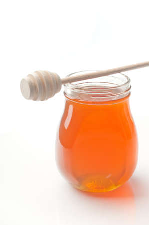 Jar of honey with wooden drizzler isolated on white backgroundの写真素材