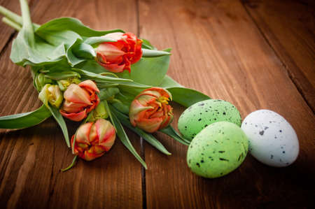birds eggs in nest with tulip flowers on vintage wooden backgroundの写真素材