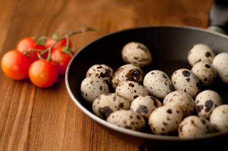 Frying pan with raw quail eggs on wooden boardsの写真素材