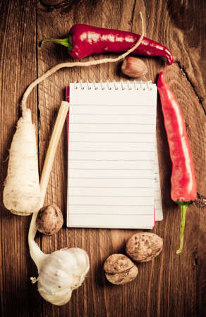 Open notebook with vegetables on the old wooden cutting boardの写真素材