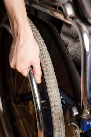 Close-up of male hand on wheel of wheelchairの写真素材