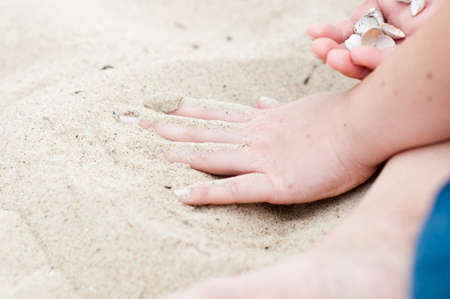 hand on the beach in the background sea shellsの写真素材
