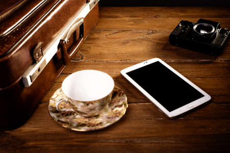 Suitcase and old camera, tablet, phone and a cup of coffee.の写真素材