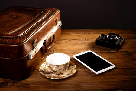 Suitcase and old camera, tablet, phone and a cup of coffee.の写真素材