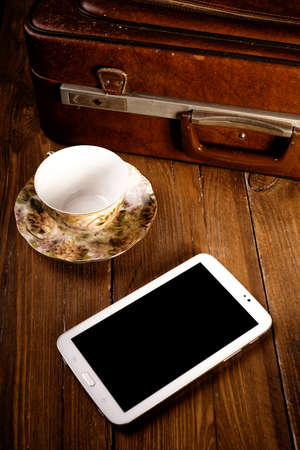 Suitcase and old camera, tablet, phone and a cup of coffee.の写真素材