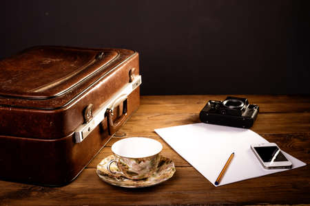 Suitcase and old camera, tablet, phone and a cup of coffee.の写真素材