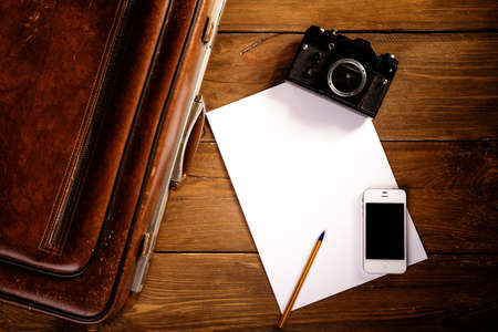 Suitcase and old camera, tablet, phone and a cup of coffee.の写真素材