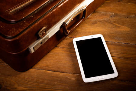 Suitcase and old camera, tablet, phone and a cup of coffee.の写真素材