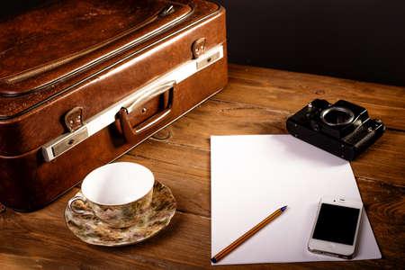 Suitcase and old camera, tablet, phone and a cup of coffee.の写真素材
