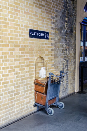 LONDON - MAY 31: Kings Cross station wall visited by fans of Harry Potter to photograph sign for platform nine and three quarters with trolley, London, May 31, 2015.のeditorial素材