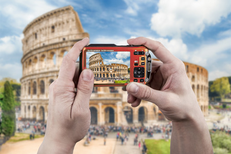 Hands on a point and shoot photo camera taking picture of the Colosseum in Rome, Italy. Concept for travel photographyの写真素材