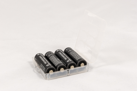 Four unbranded black AA rechargeable batteries in trasparent case, isolated on white backgroundの写真素材