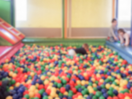 Defocused background with colorful plastic balls in children's playground pool. Intentionally...