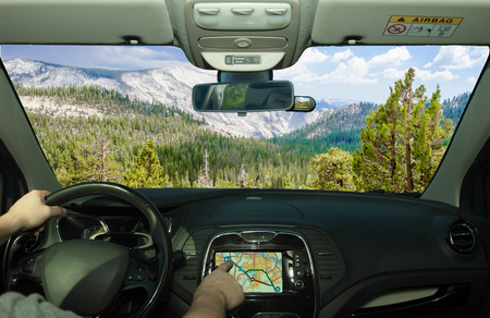 Driving a car while using the touch screen of a GPS navigation system in Yosemite National Park, California, USAの写真素材