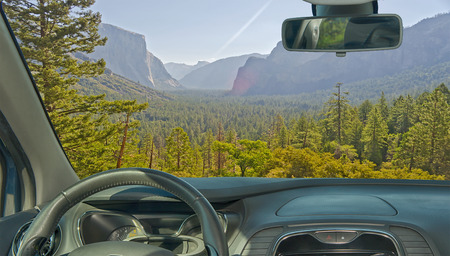 Looking through a car windshield with view of a beautiful green valley in Yosemite National Park,...