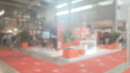 Defocused background of a trade show with people visiting the commercial exhibition. Intentionally blurred post production for bokeh effectの写真素材