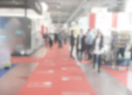 Defocused background of a trade show with people visiting the commercial exhibition. Intentionally blurred post production for bokeh effectの写真素材