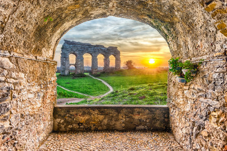 Scenic rock arch balcony overlooking the iconic ruins of Parco degli Acquedotti, Rome, Italyの写真素材