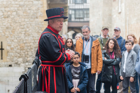 LONDON - APRIL 13, 2022: A Yeomen Warder talking to visitors during a tour of the historic Tower of...